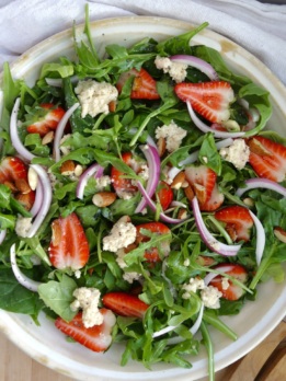 Overhead shot of strawberry arugula salad with vegan ricotta and red onion.
