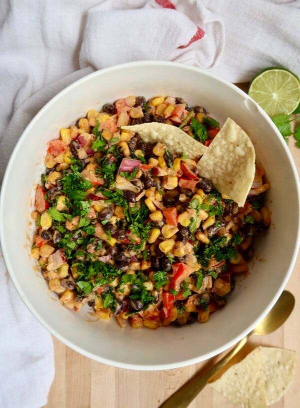 Bowl with black bean and corn salad with chips in it.
