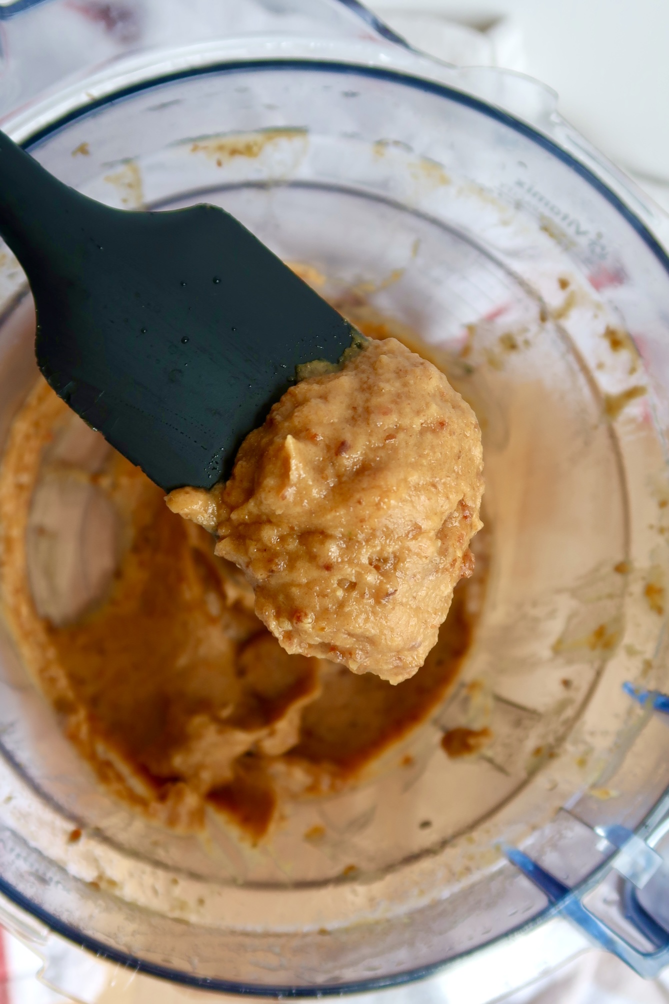 Dates blended in a food processor with a spatula scooping some.
