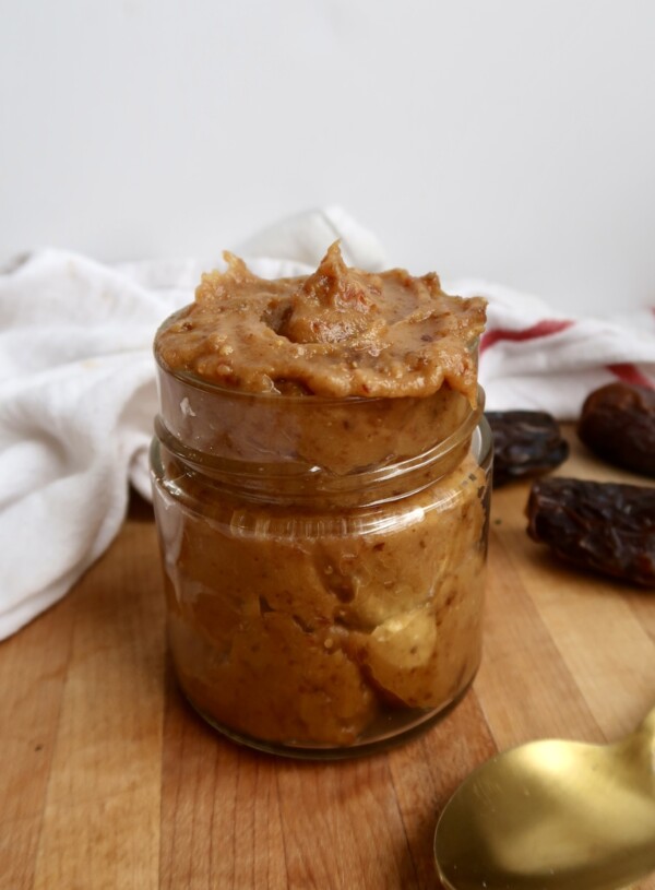 Jar of date paste with dates in the background.