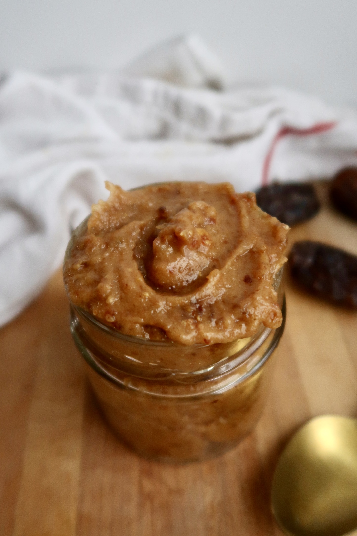 Jar of date paste with dates in the background.