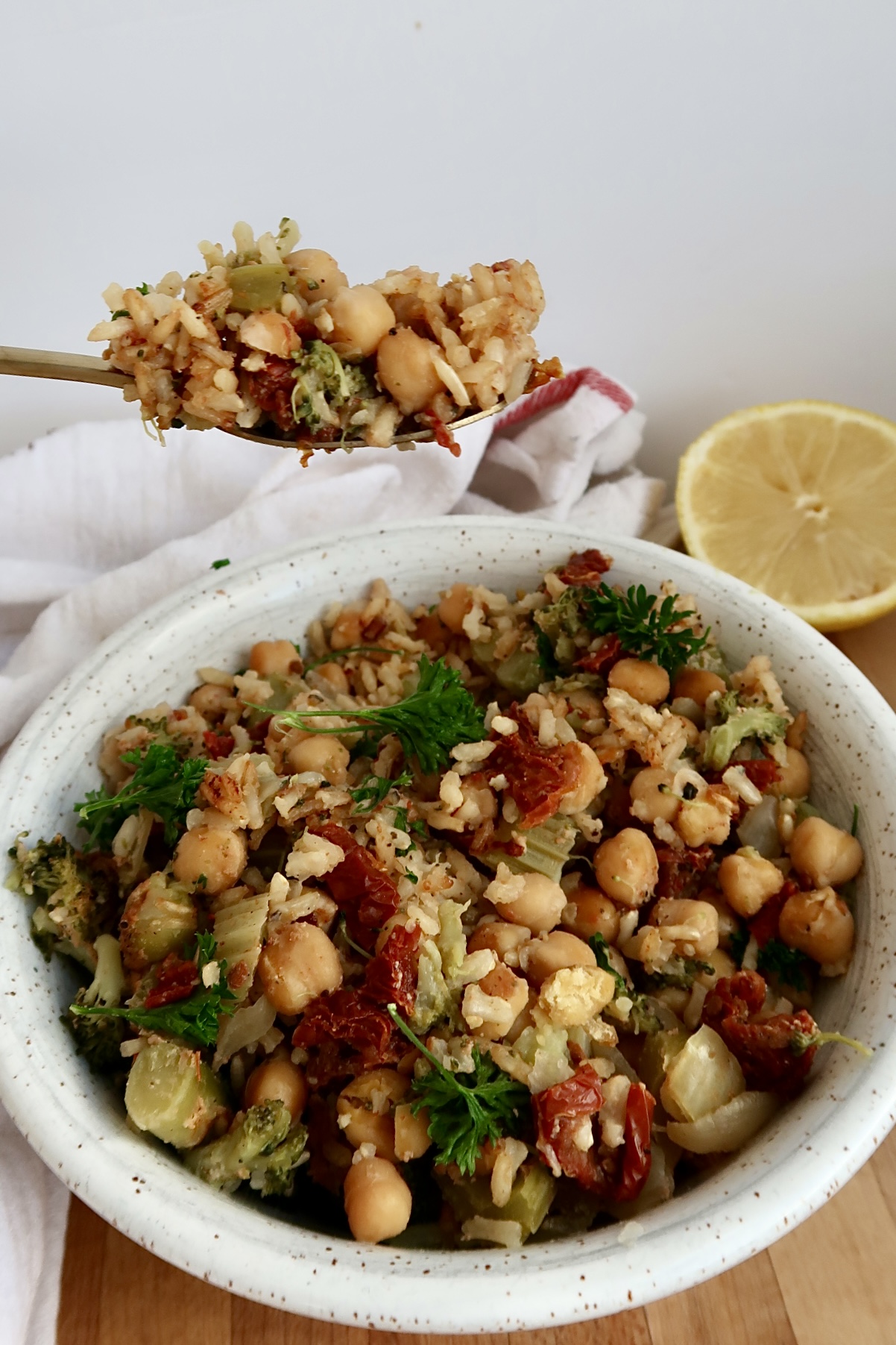 Side view of chickpea casserole in a white bowl with a spoon scooping some.