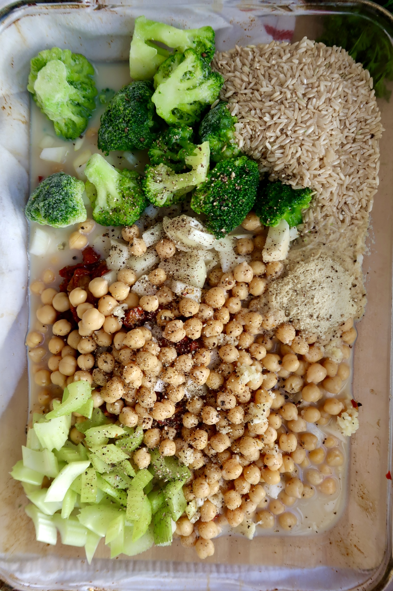 Casserole dish with rice, chickpeas, broccoli, celery and sundried tomatoes.