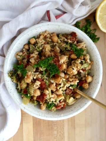 Chickpea casserole in a white bowl with a spoon scooping some.