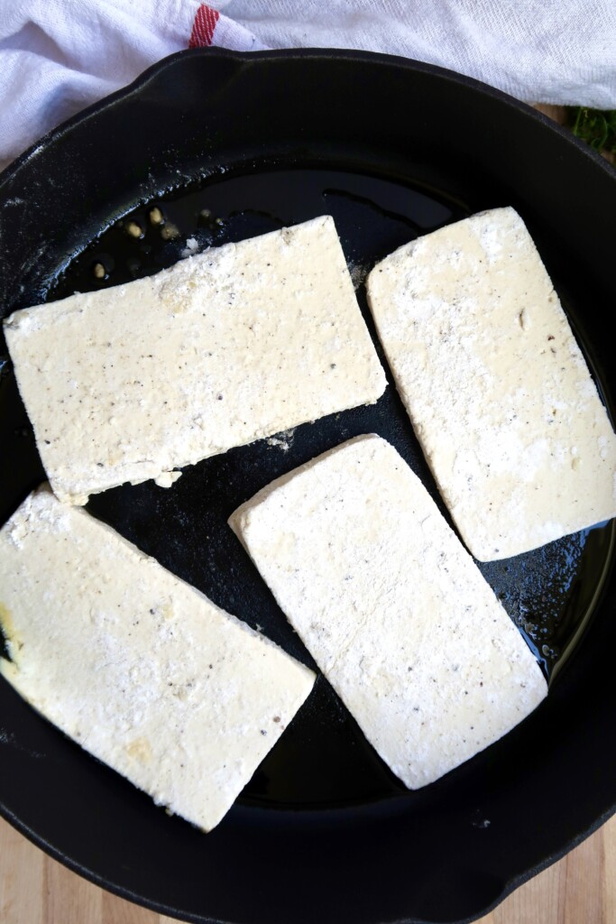 Pan with slices of tofu with flour on the outside.