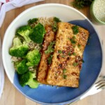 Bowl with two pieces of ginger sesame tofu with rice and broccoli.