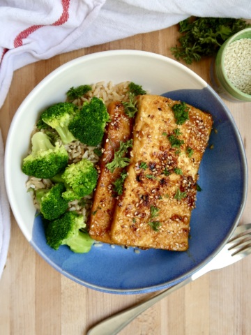 Bowl with two pieces of ginger sesame tofu with rice and broccoli.