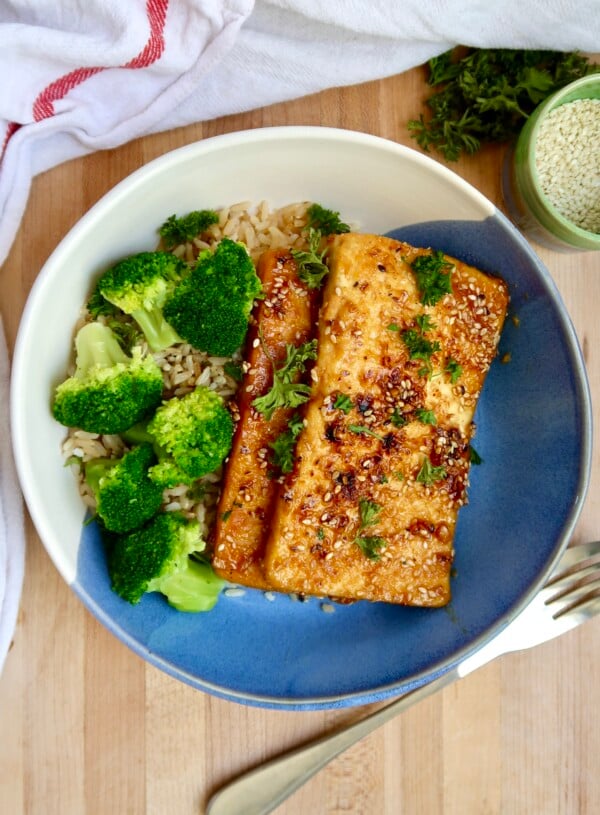 Bowl with two pieces of ginger sesame tofu with rice and broccoli.