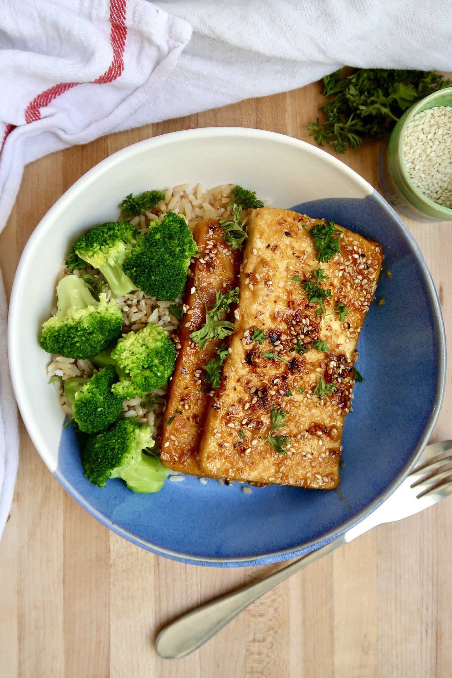 Bowl with two pieces of ginger sesame tofu with rice and broccoli.