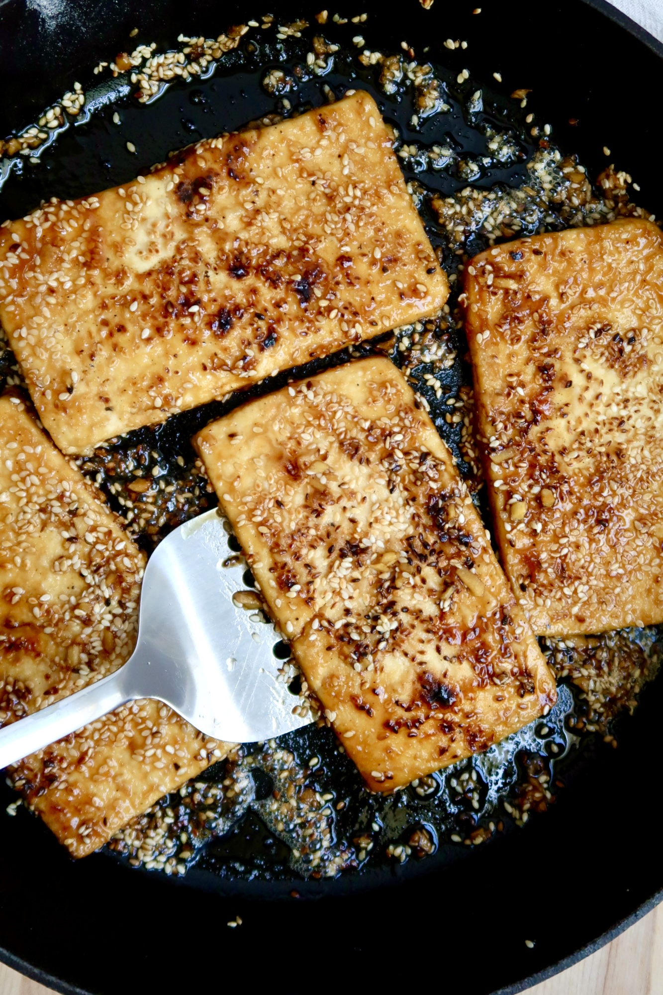 Pan of ginger sesame tofu with a spatula.