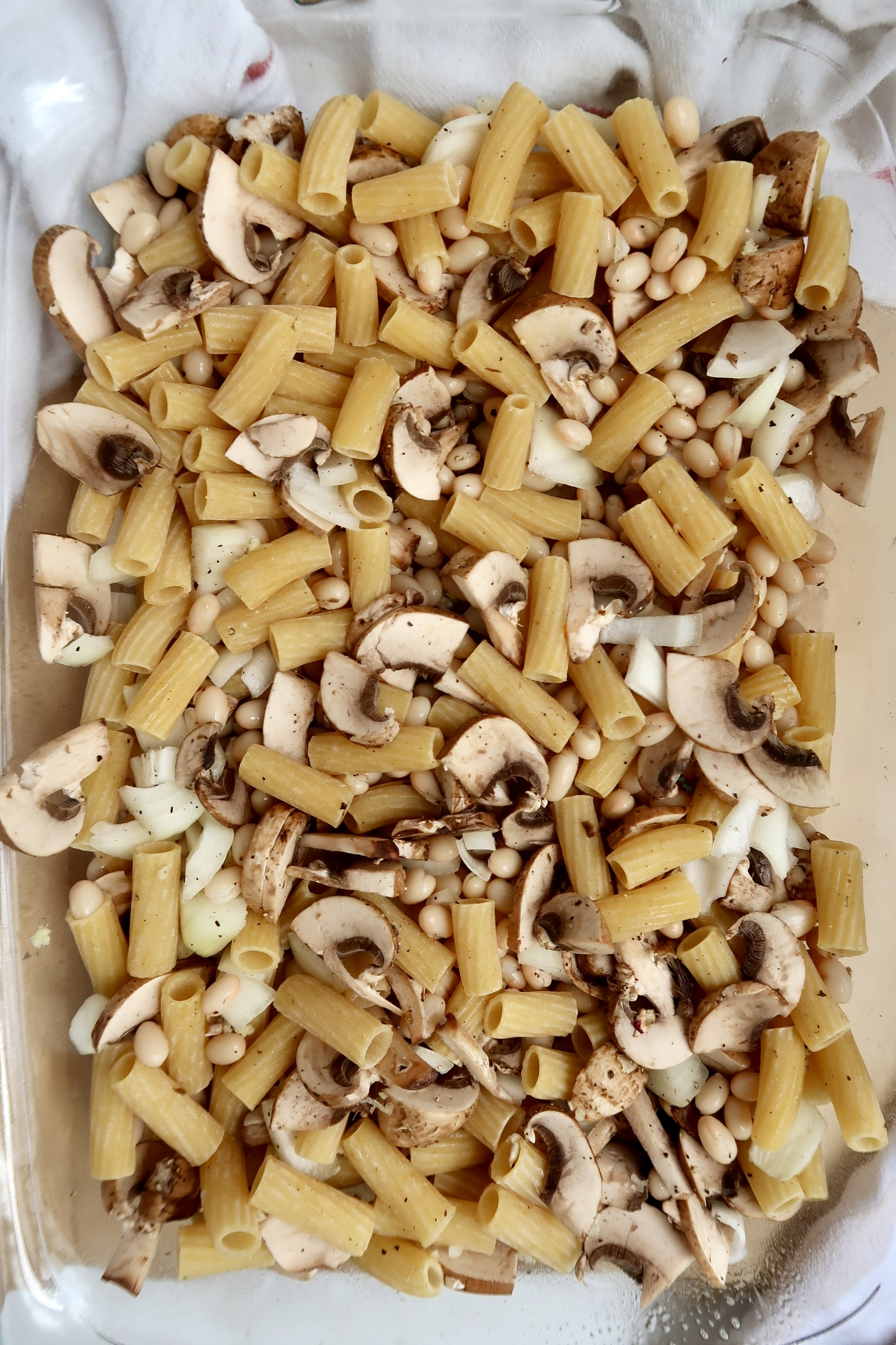 Casserole dish with pasta, mushrooms, diced onion.