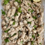 Cooked pasta in a casserole dish with mushroom and parsley on top.