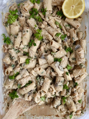 Cooked pasta in a casserole dish with mushroom and parsley on top.
