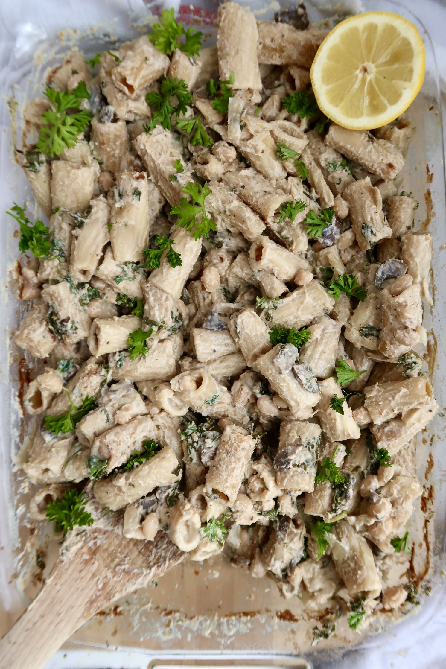 Cooked pasta in a casserole dish with mushroom and parsley on top.