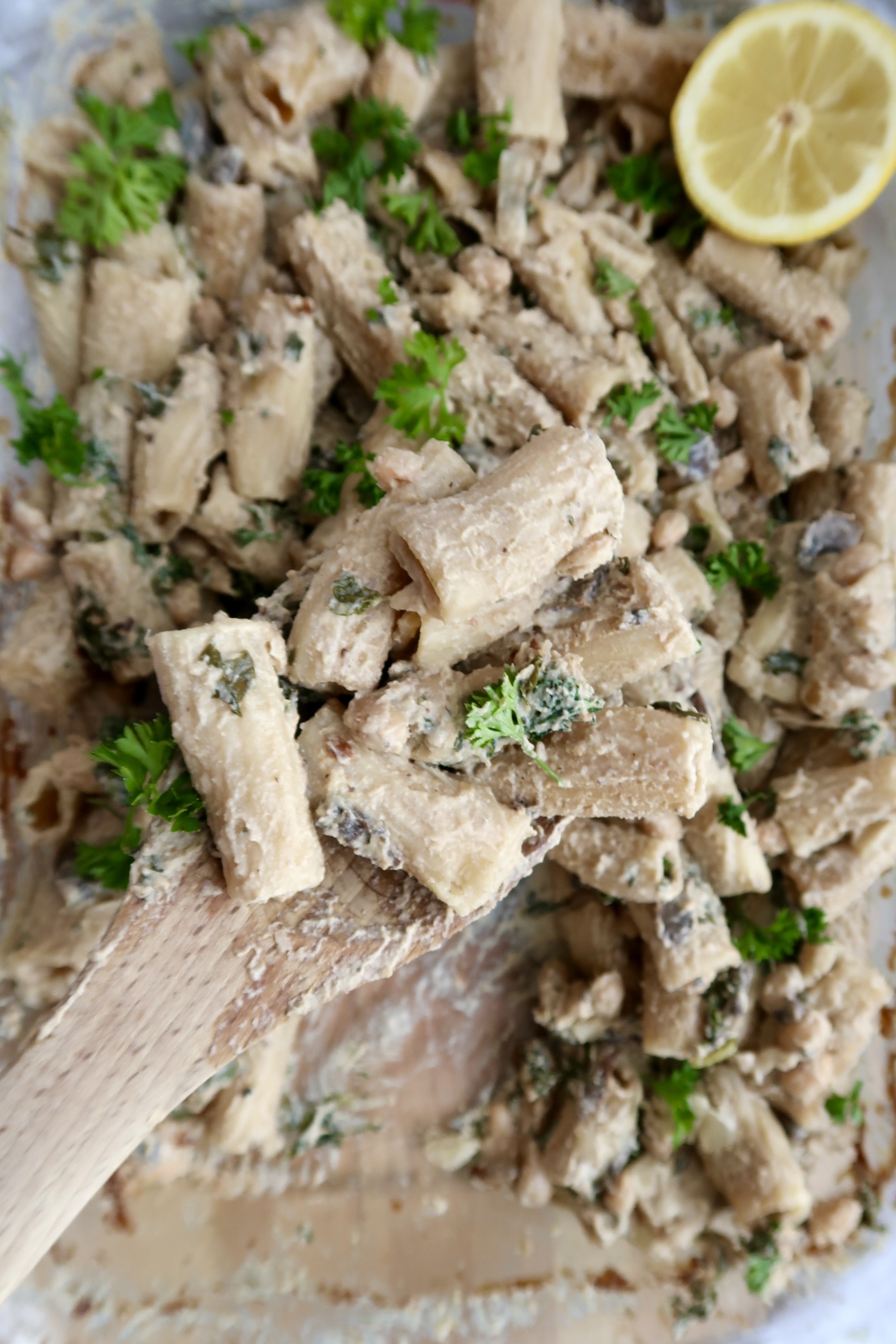 Creamy pasta being picked up by a spoon with parsley on top.