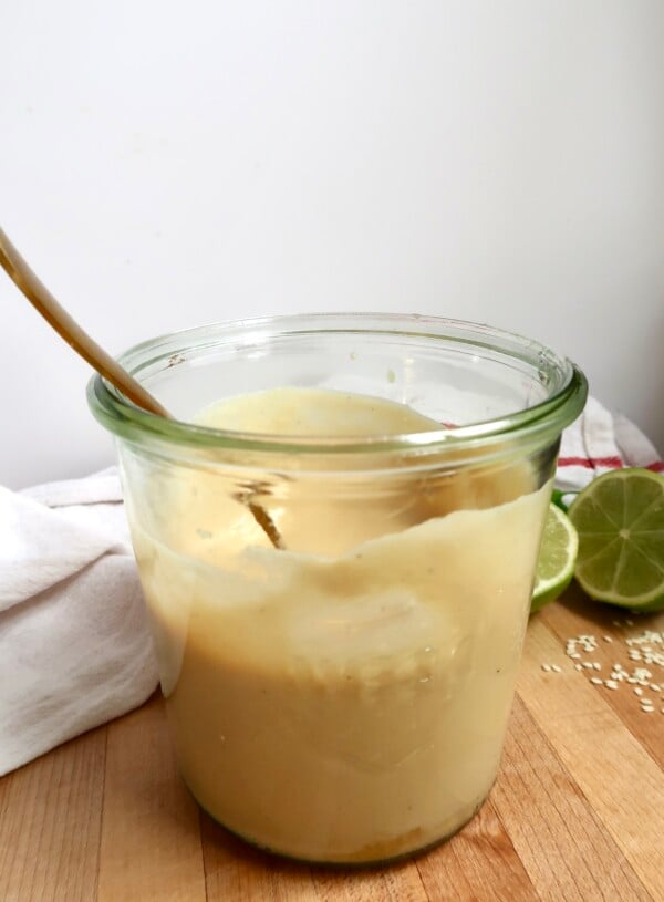 Side view of jar with creamy ginger dressing inside and a spoon.