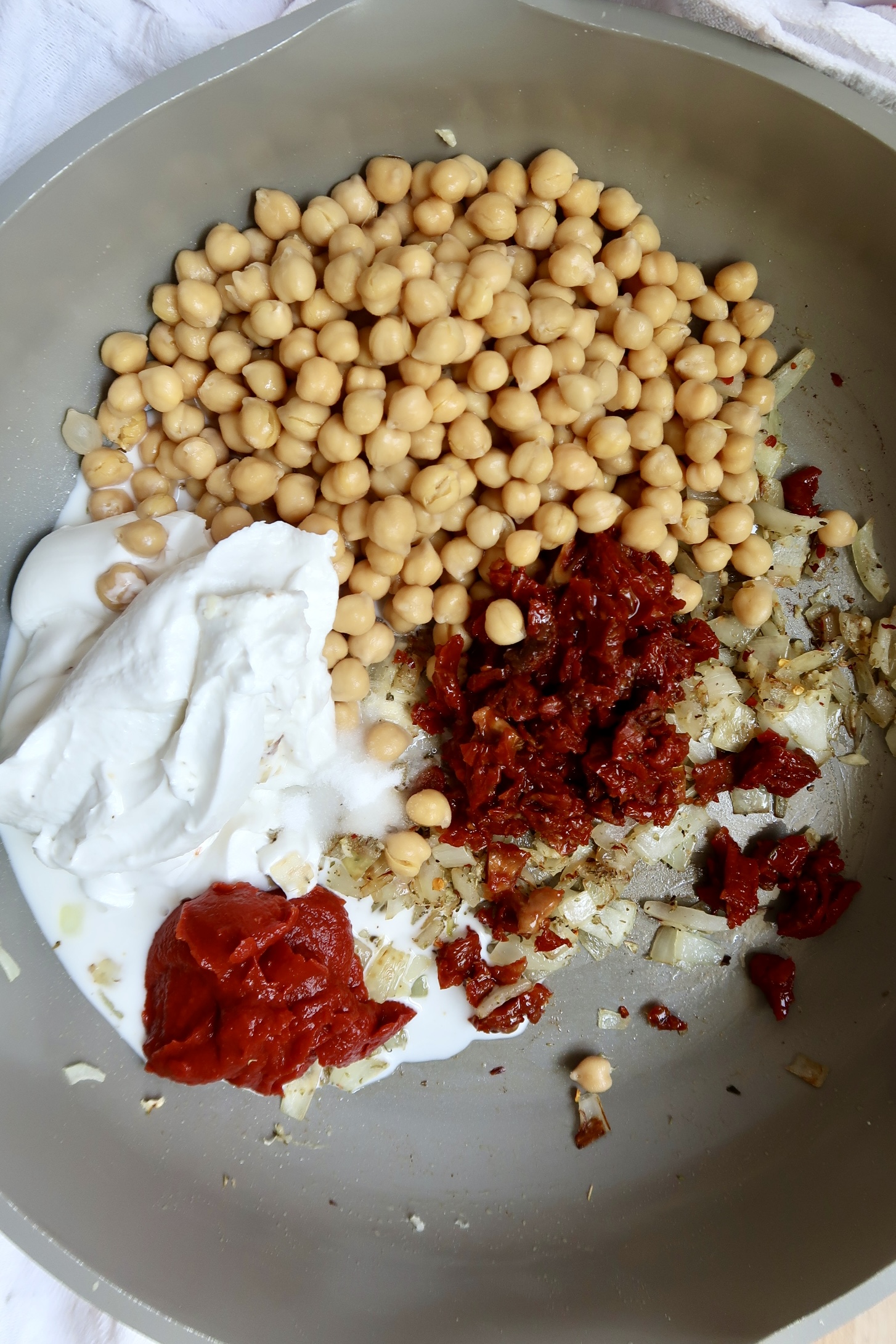 Pan with onion, garlic, chickpeas, coconut milk, sundried tomatoes, and tomato paste.
