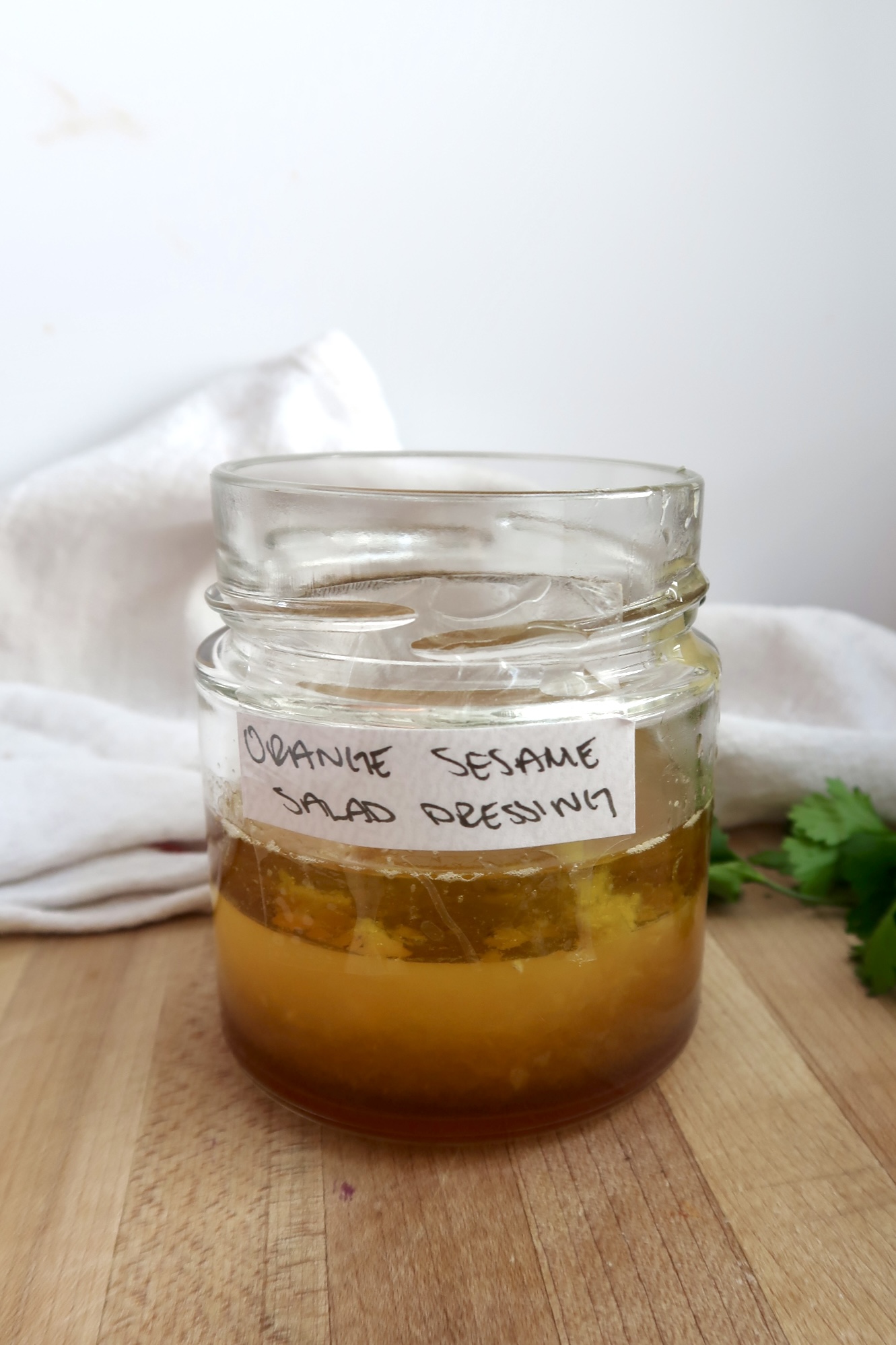 Jar with orange juice, olive oil, and garlic that's labeled Orange Sesame Salad Dressing.