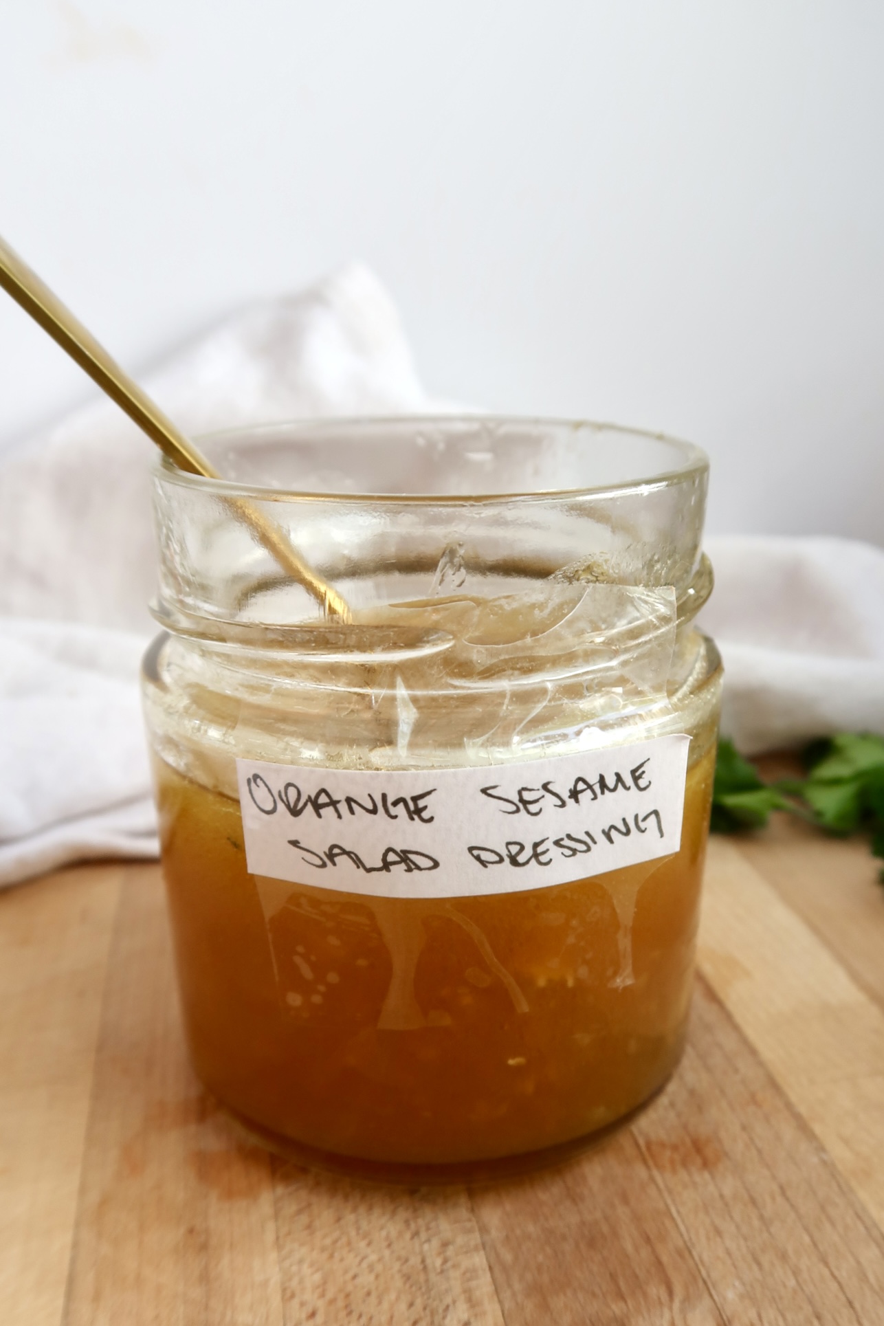 Jar labaled Orange Sesame Salad Dressing with a dressing inside and a spoon.