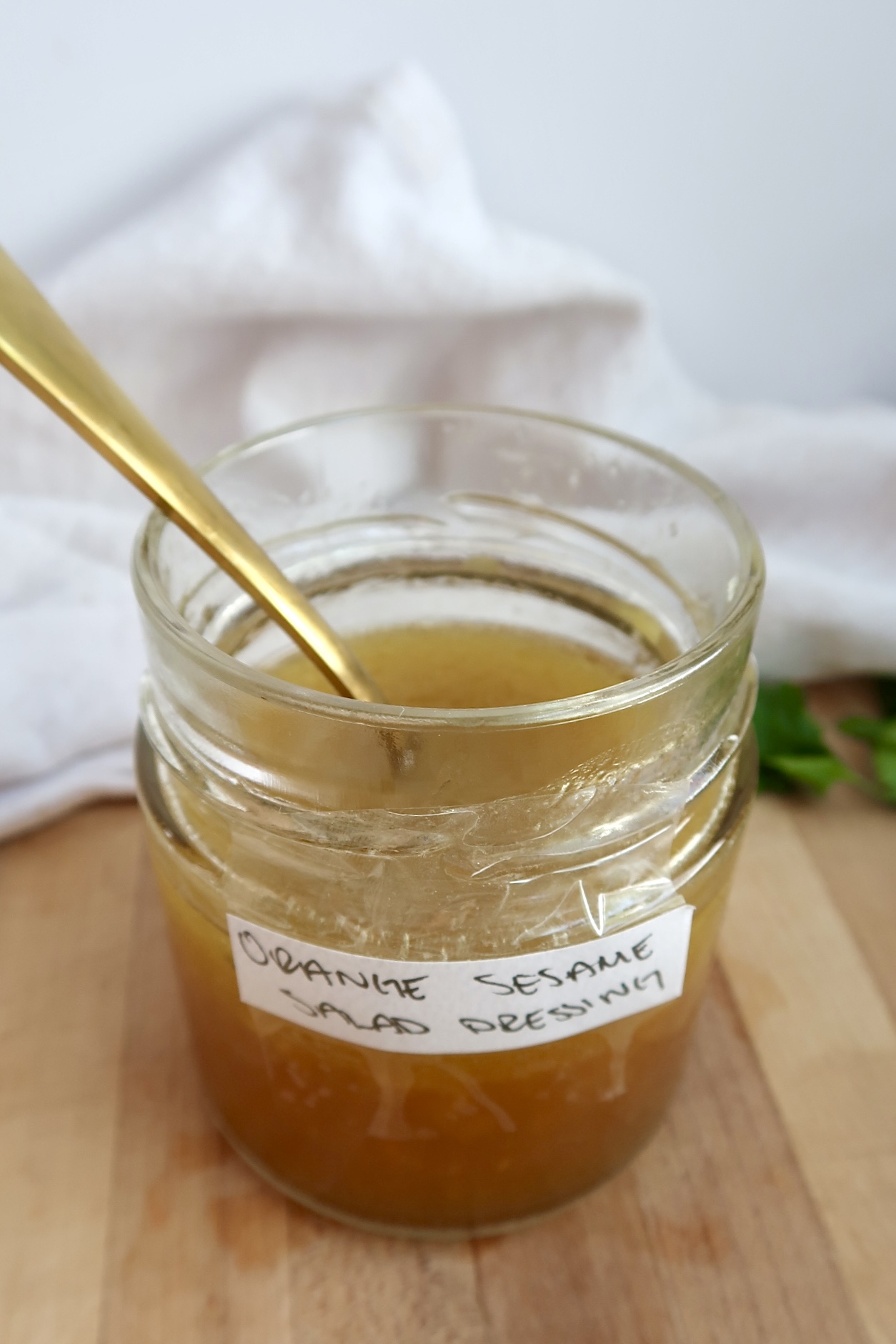 Jar labaled Orange Sesame Salad Dressing with a dressing inside and a spoon.