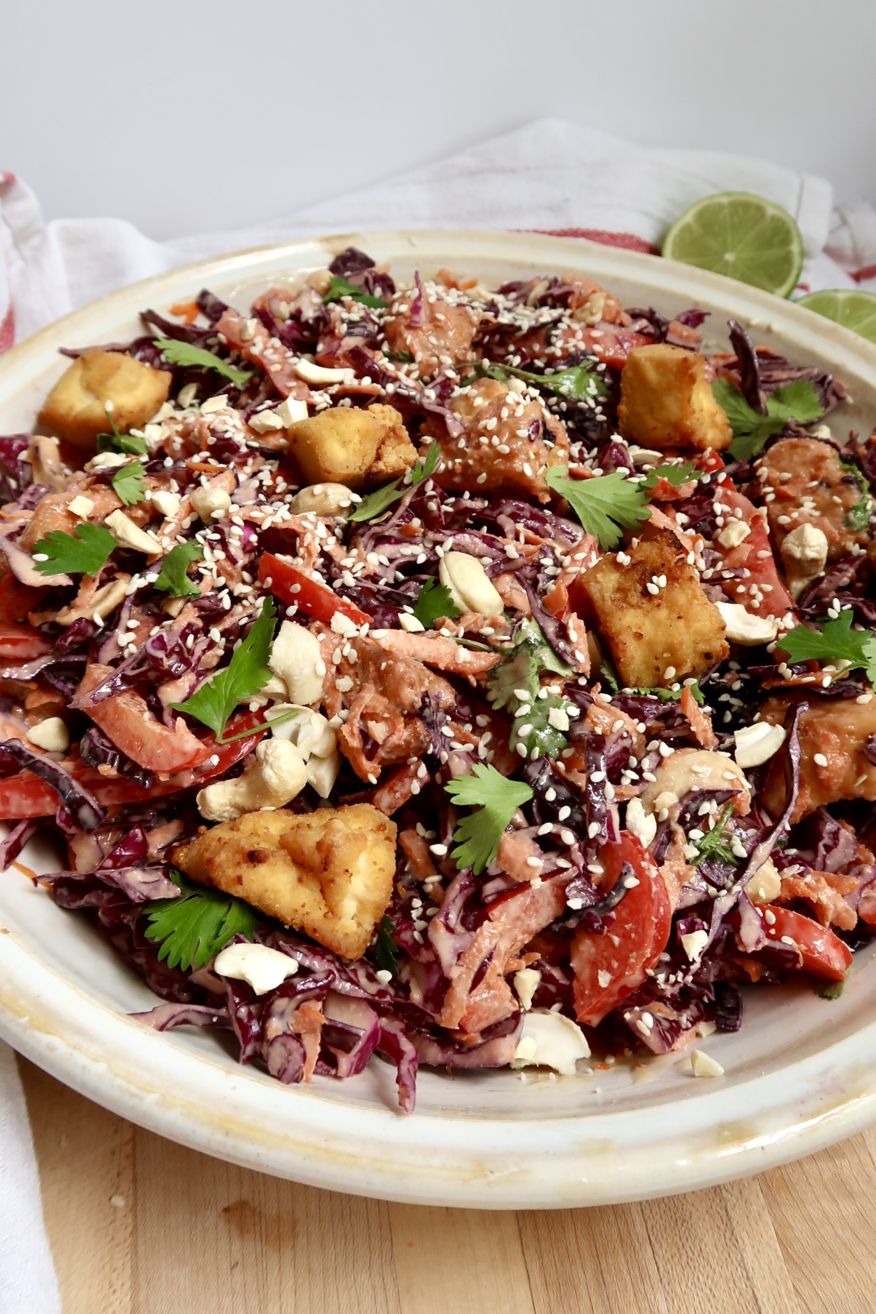 Top-down shot of a fully assembled salad with purple cabbage, crispy tofu, chopped herbs, and sesame seeds.