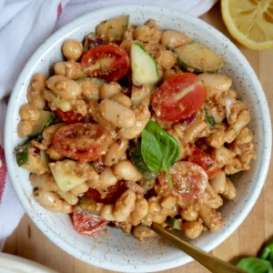 Another angle of the same hearty white bean salad with juicy tomatoes and crisp cucumbers, topped with fresh basil leaves