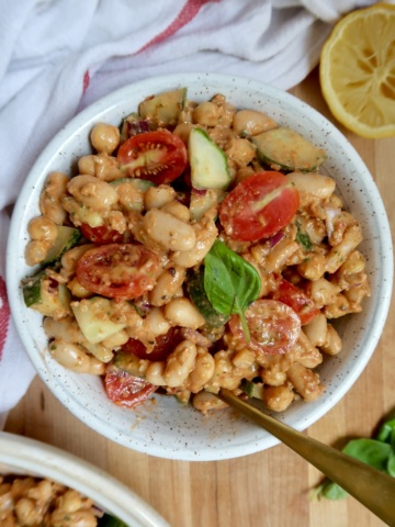 Another angle of the same hearty white bean salad with juicy tomatoes and crisp cucumbers, topped with fresh basil leaves