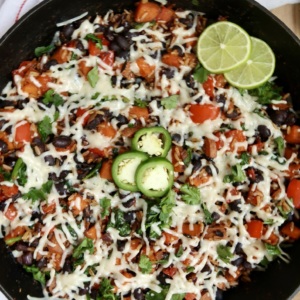 Finished cheesy skillet garnished with lime and jalapeño slices