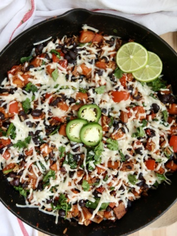 Finished cheesy skillet garnished with lime and jalapeño slices