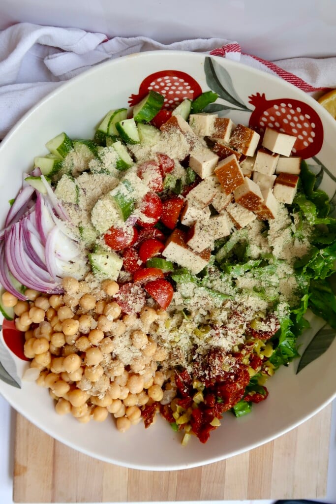 Bowl with chickpeas, onion, tomato, cucumber, romaine, tofu and nutritional yeast.