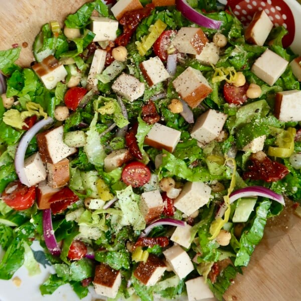 Bowl with salad with tofu, cherry tomatoes, chickpeas, red onion, sundried tomatoes mixed in.