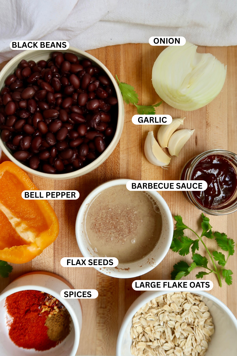 Overhead shot of black beans, garlic, BBQ sauce, onion, and other ingredients prepped in bowls for making black bean burgers.