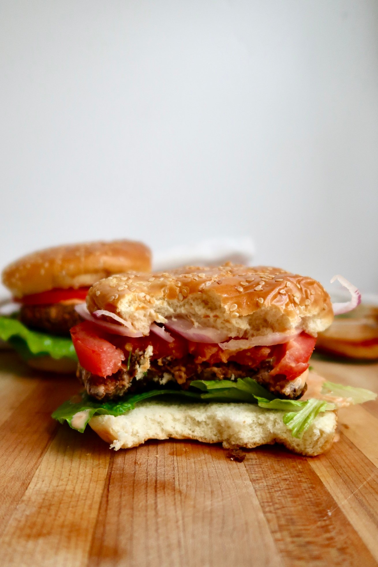 A juicy black bean burger cut in half, showing the flavorful interior, stacked with lettuce, tomato, and sauce on a sesame bun.