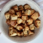 Golden brown croutons in a speckled bowl – Freshly baked and crispy with visible seasoning.