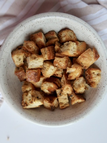 Golden brown croutons in a speckled bowl – Freshly baked and crispy with visible seasoning.