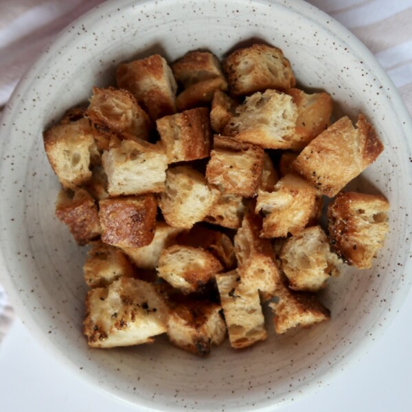 Golden brown croutons in a speckled bowl โ Freshly baked and crispy with visible seasoning.