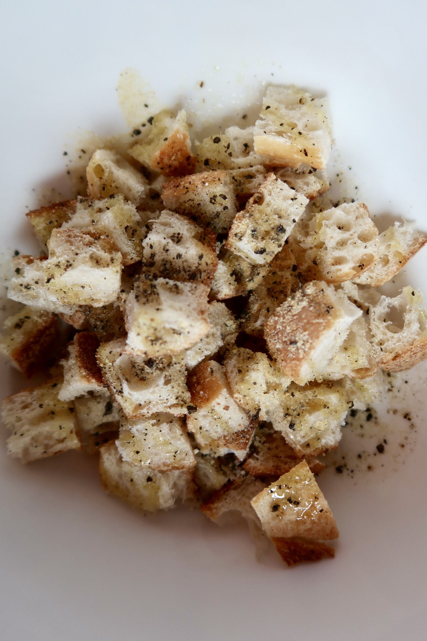 Cubed bread pieces tossed with herbs and oil, ready to be baked or air-fried.