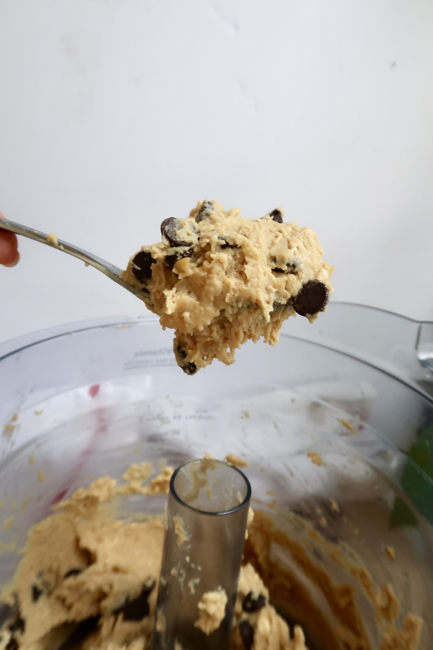 Spoonful of chickpea cookie dough being lifted from a food processor.