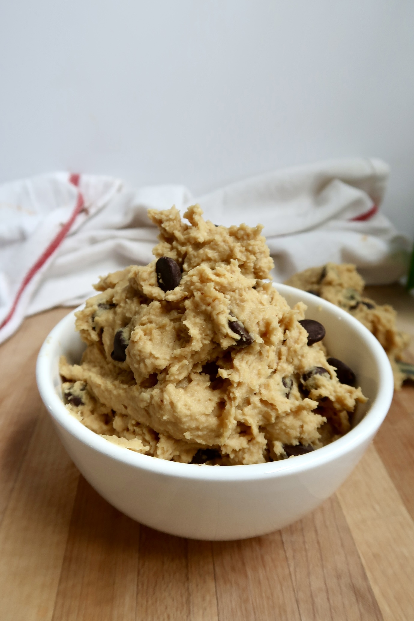 Bowl of chickpea cookie dough with chocolate chips on a white background.