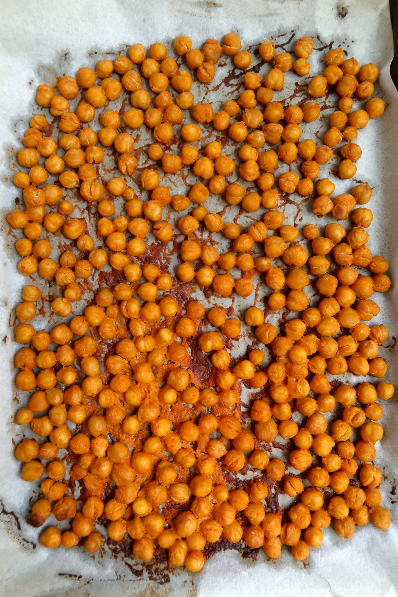 Overhead angle of roasted chickpeas on parchment paper.