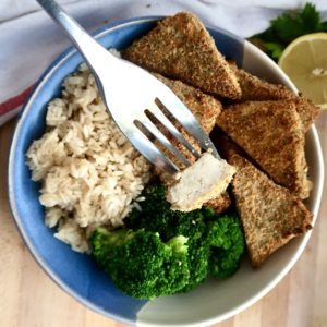 Bowl with breaded tofu, broccoli and rice and a fork piercing a piece of the tofu.