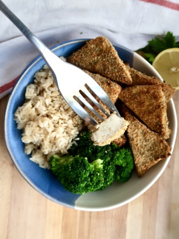Bowl with breaded tofu, broccoli and rice and a fork piercing a piece of the tofu.
