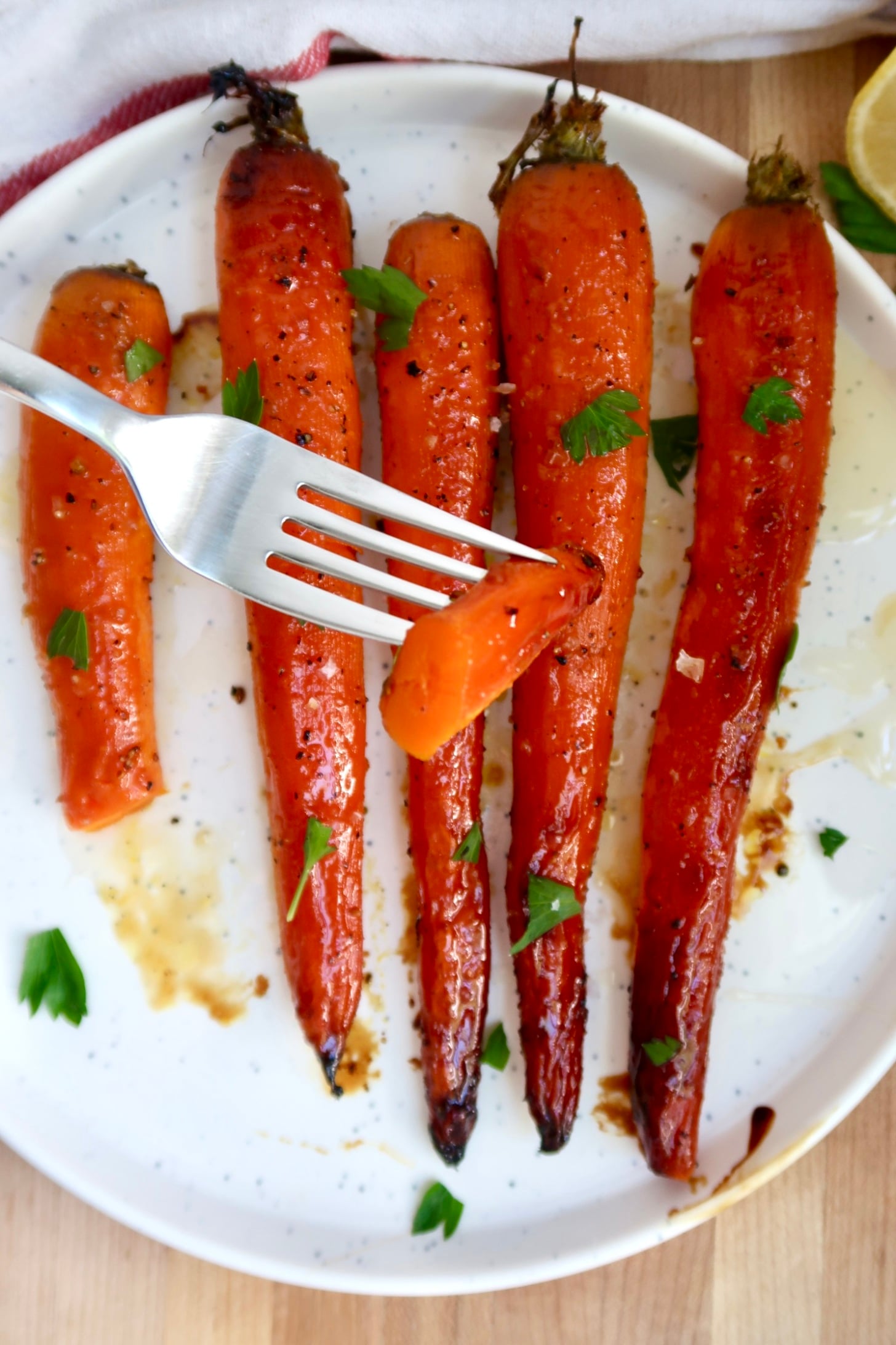 Fork with a piece of carrot on it and roasted carrots in the background.