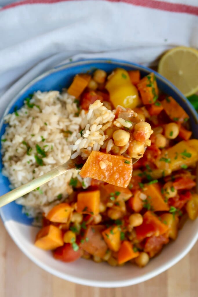 Bowl with curry, rice, parsley and a spoon scooping some.