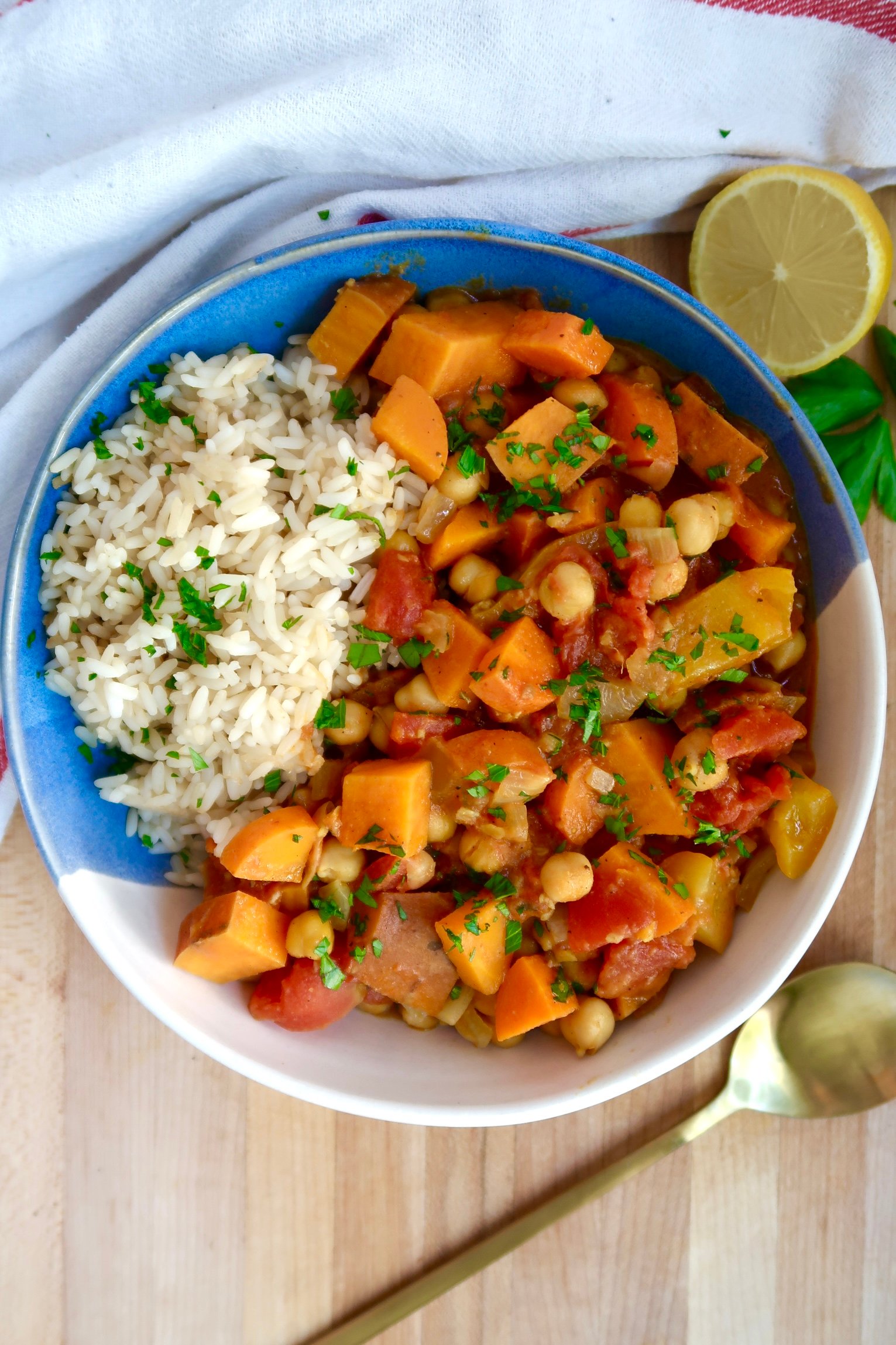 Bowl with curry, rice, and parsley on top with lemon on the side. 
