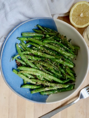 Overhead shot of cooked green beans with a lemon to the side