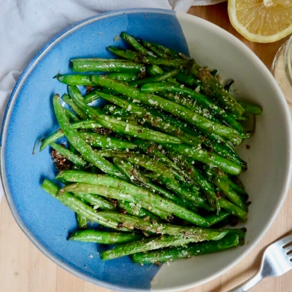 Overhead shot of cooked green beans with a lemon to the side