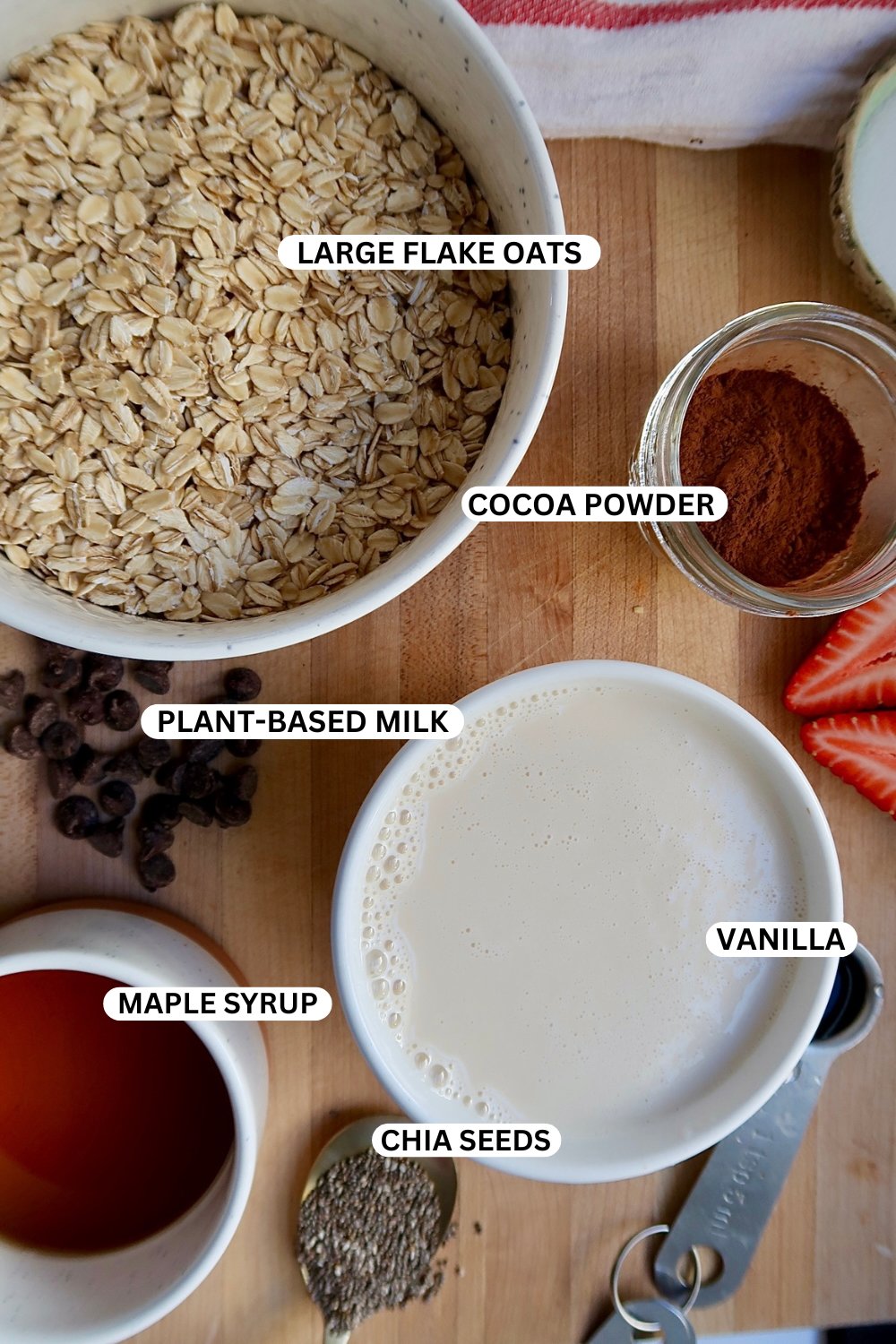 Oats, soy milk, cocoa powder, maple syrup and chia seeds labaled on a cutting board. 