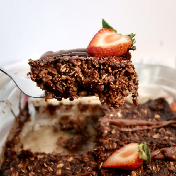 Pan of chocolate baked oats and a slice of chocolate oats being lifted by a spatula.