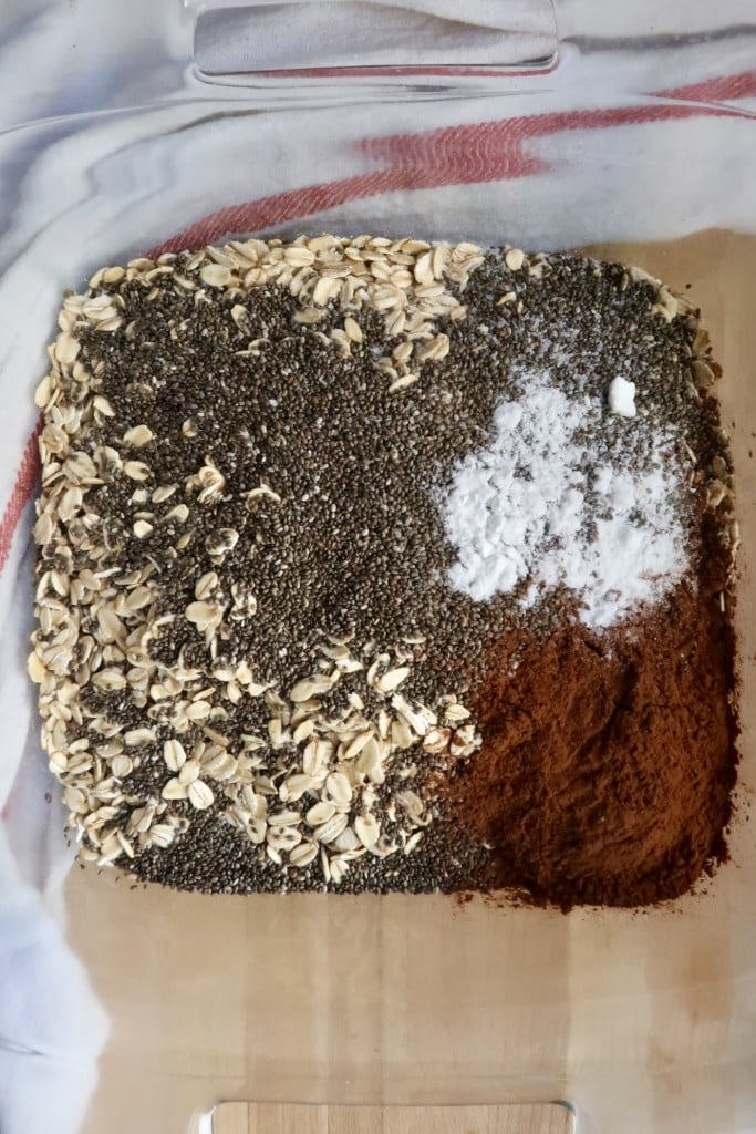 Baking dish with oats, chia seeds, baking soda, salt and cocoa powder in it.